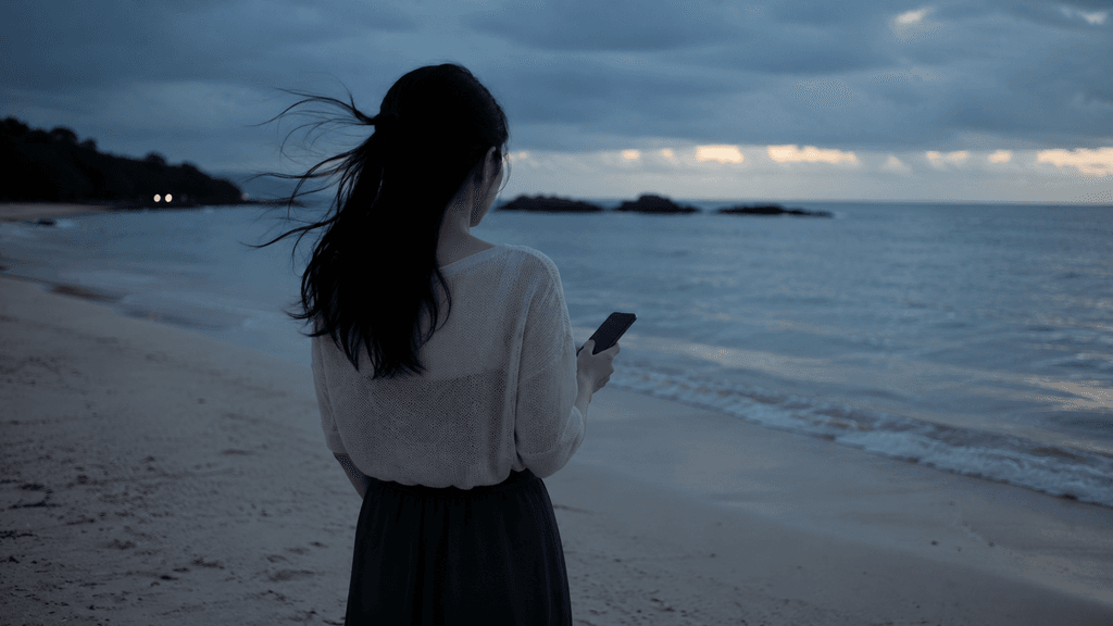 沖縄の海を夕方に一人で見つめながら孤独を感じる県外出身の移住者女性